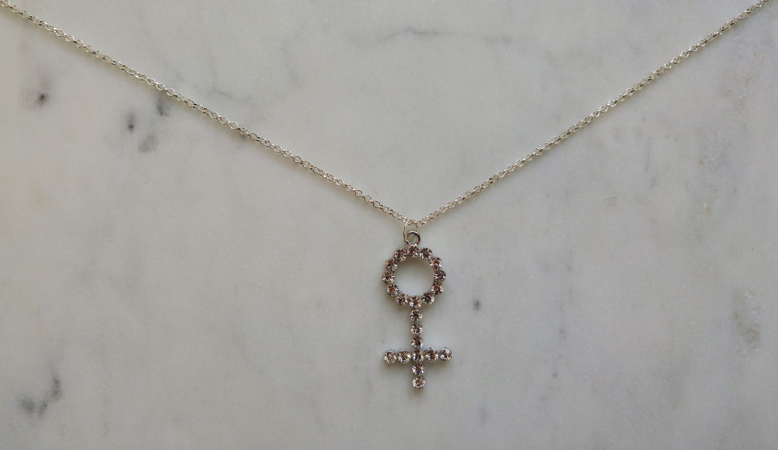 Silverfärgat halsband med en venussymbol i strass