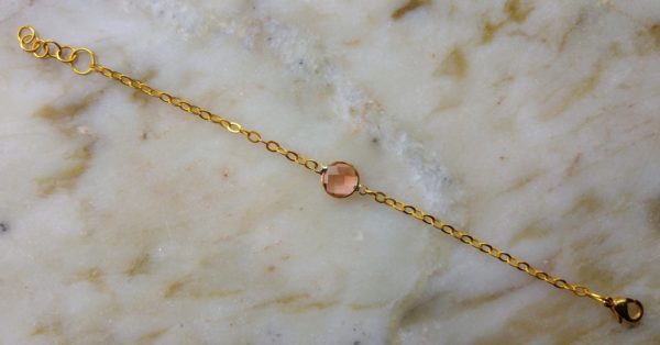 Guldfärgad metallkedja med en laxrosa glassten
