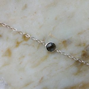 Silverfärgad metallkedja med en glassten i olika färger
