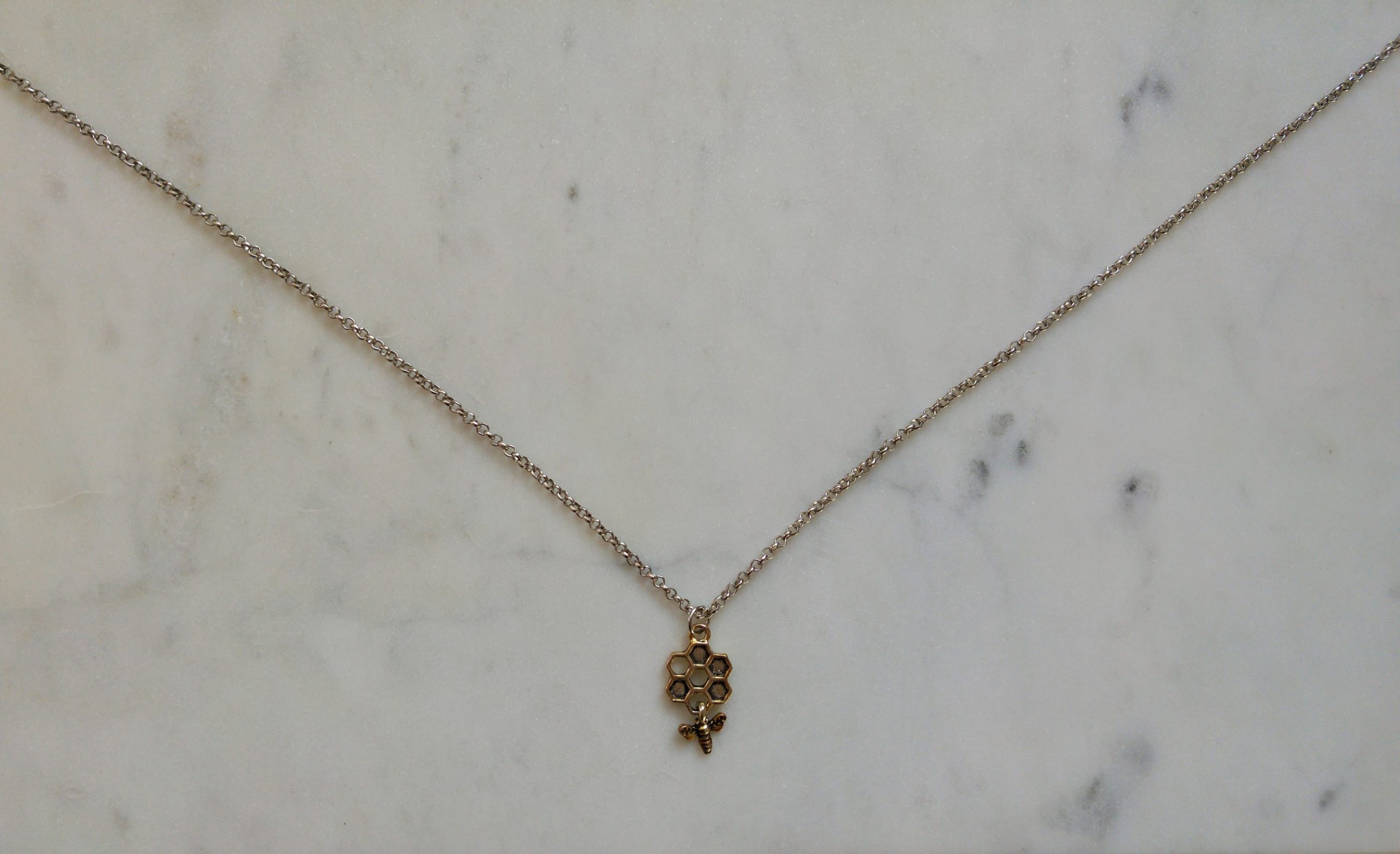 Antiksilverfärgat halsband med en vaxkaka och ett litet bi