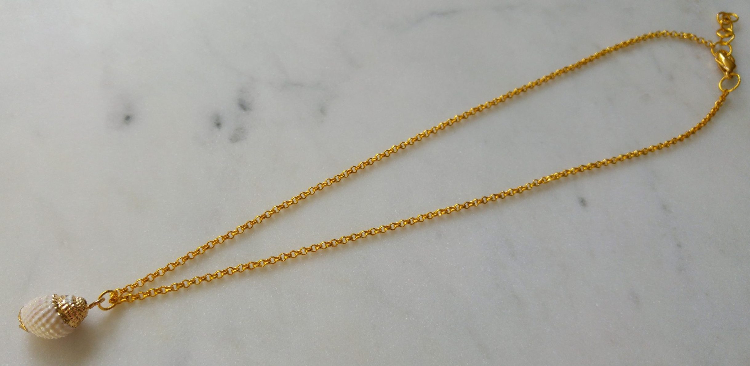 Guldfärgat halsband med en vit snäcka - Bild 2