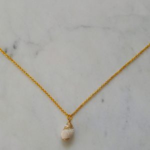 Guldfärgat halsband med en vit snäcka