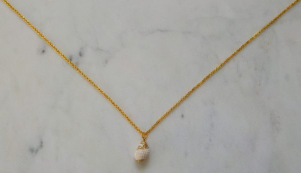 Guldfärgat halsband med en vit snäcka