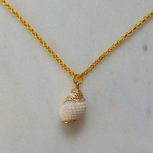 Guldfärgat halsband med en vit snäcka