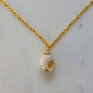 Guldfärgat halsband med en vit snäcka