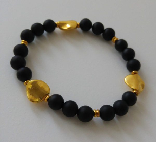Elastiskt armband med mattsvart agat, guldfärgade asymmetriska mellandelar och guldfärgade minirondeller. 